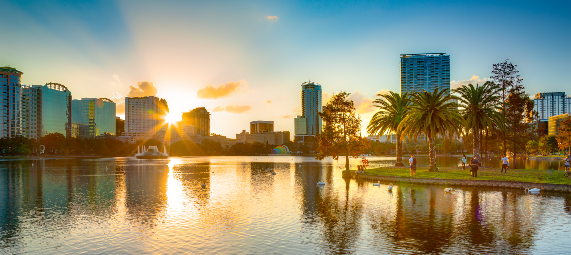 city skyline at sunset seen from a body of water and people dancing.